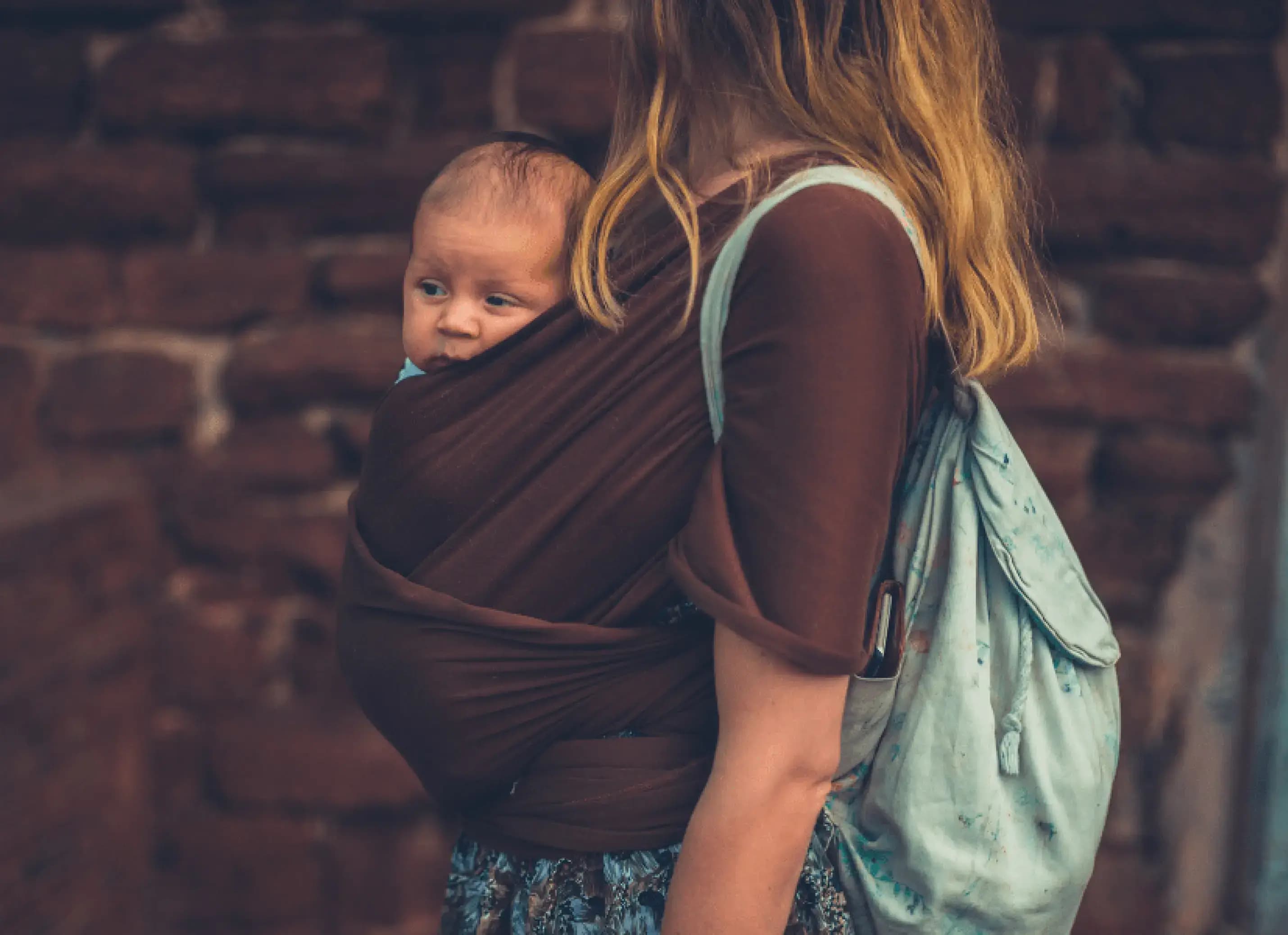 Vrouw draagt haar baby in de draagzak nadat zij de cursus dragen en hechting volgde